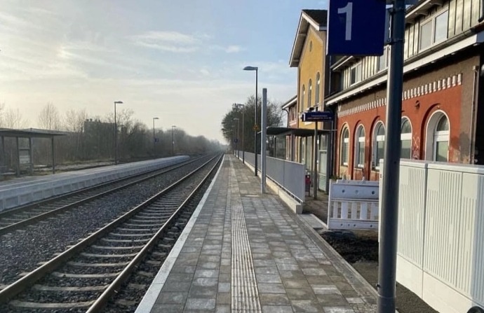 Bahnsteig mit Gleisen und einem Schild mit der Nummer 1 neben einem Gebäude an einem Bahnhof